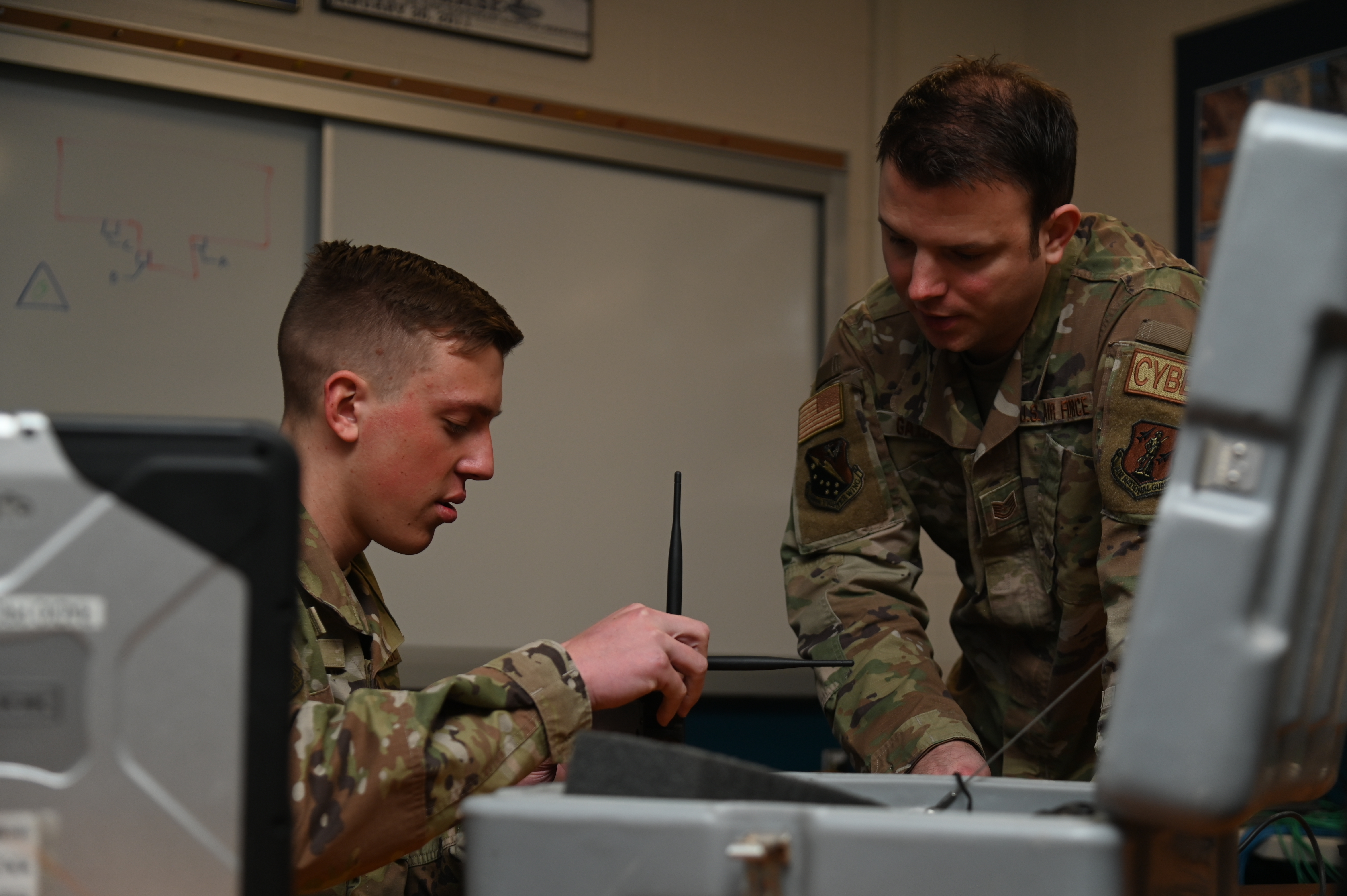Airmen inspect electrical components for radio communication.