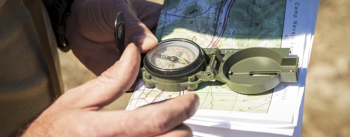holds a compass and map on a land navigation course